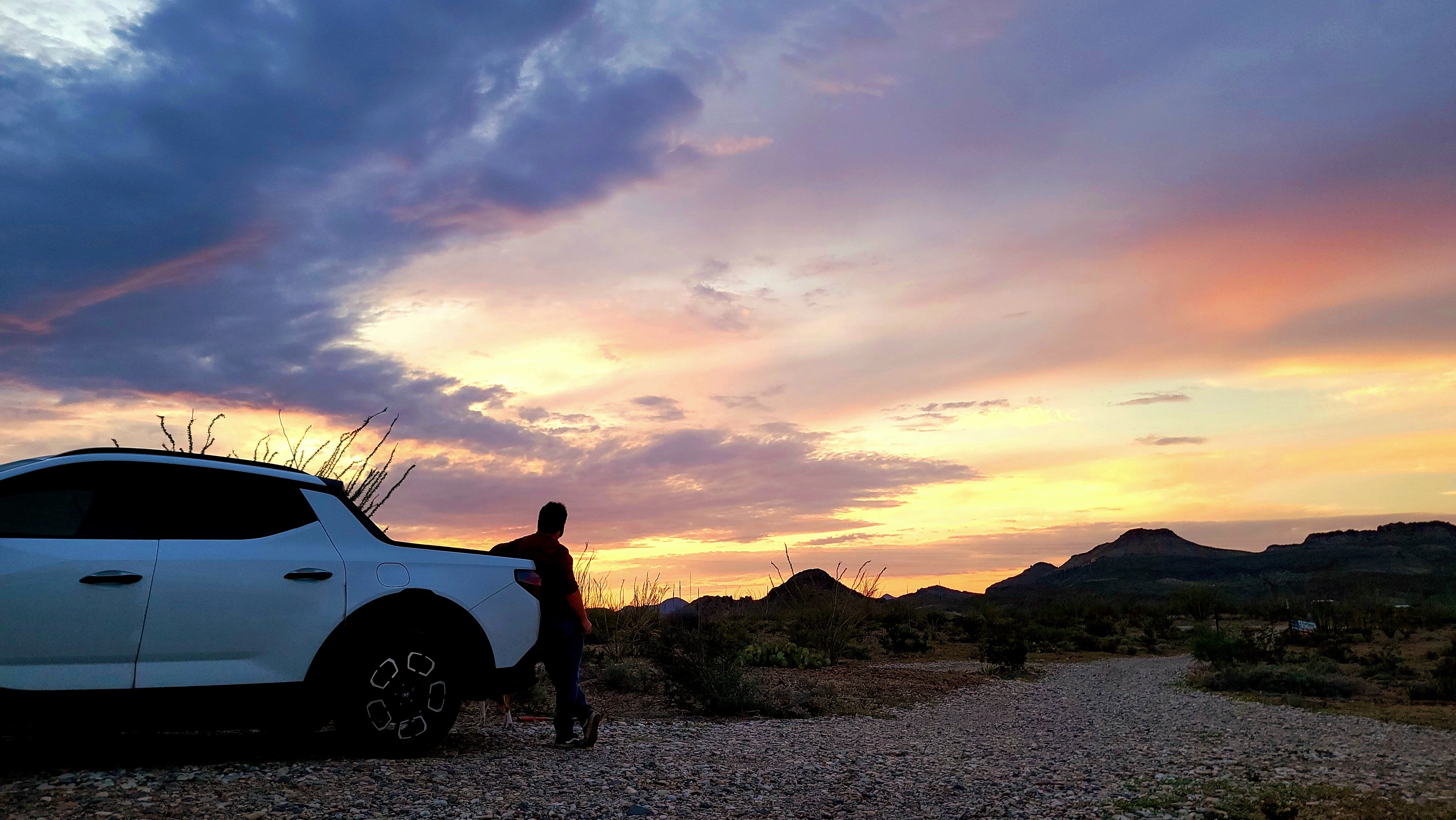 Me leaning on a white pickup truck while appreciating the sunset